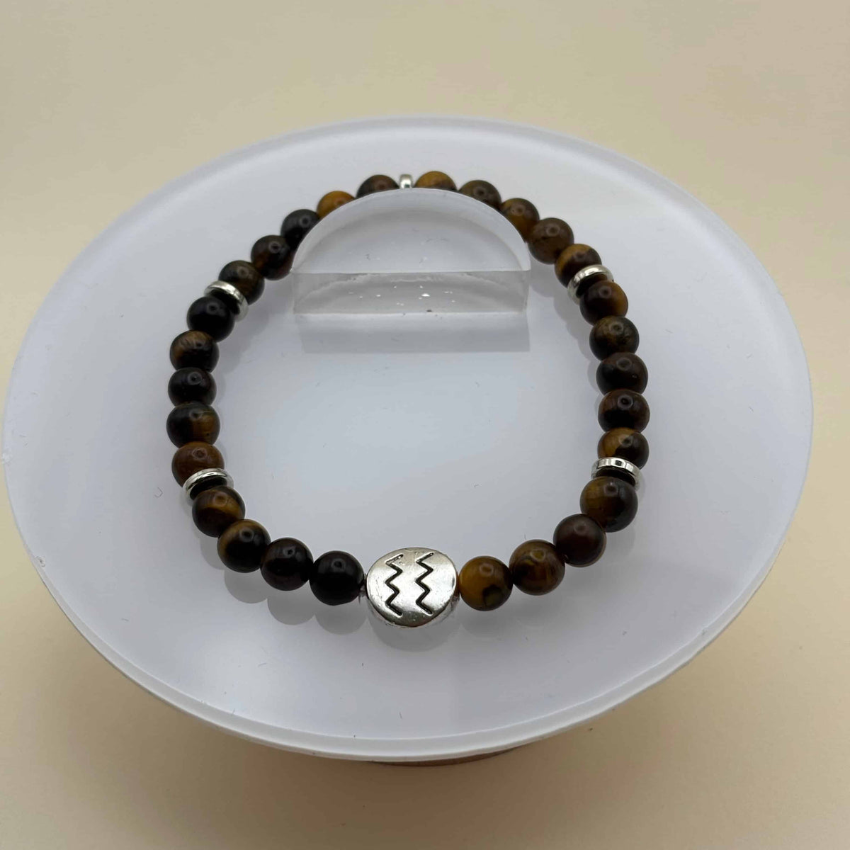 Un bracelet en perles sur élastique avec perles en porcelaine et en verre et médaillon avec le signe zodiacal du verseau