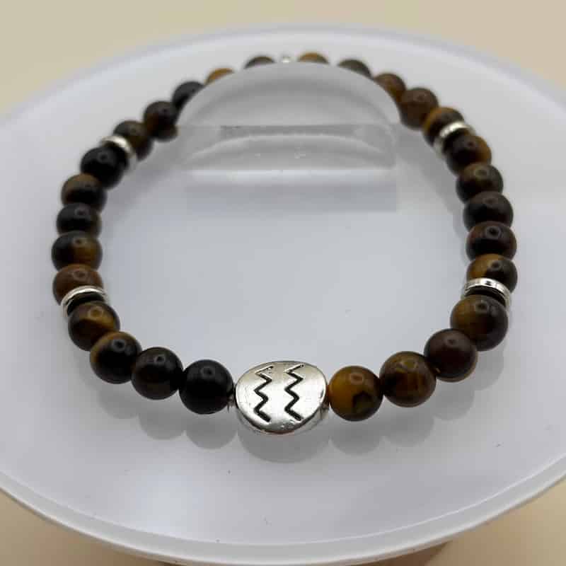 Un beau bracelet en perles sur élastique avec perles en porcelaine et en verre et médaillon avec le signe zodiacal du verseau Image