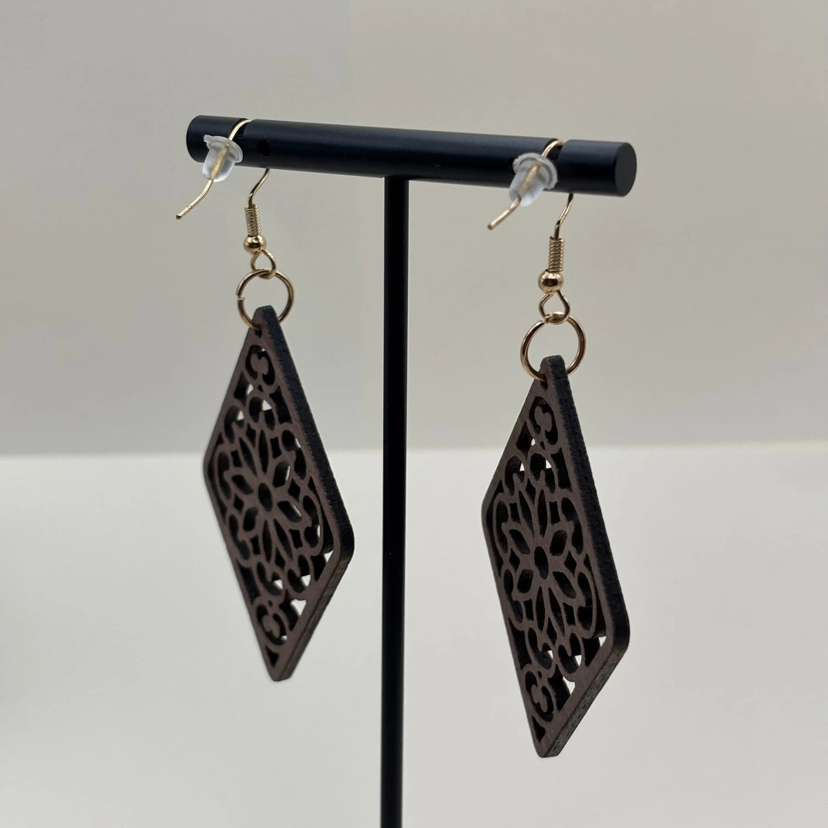 Des boucles d'oreilles avec attache dorée boucle en bois en forme de losange et motif ajouré