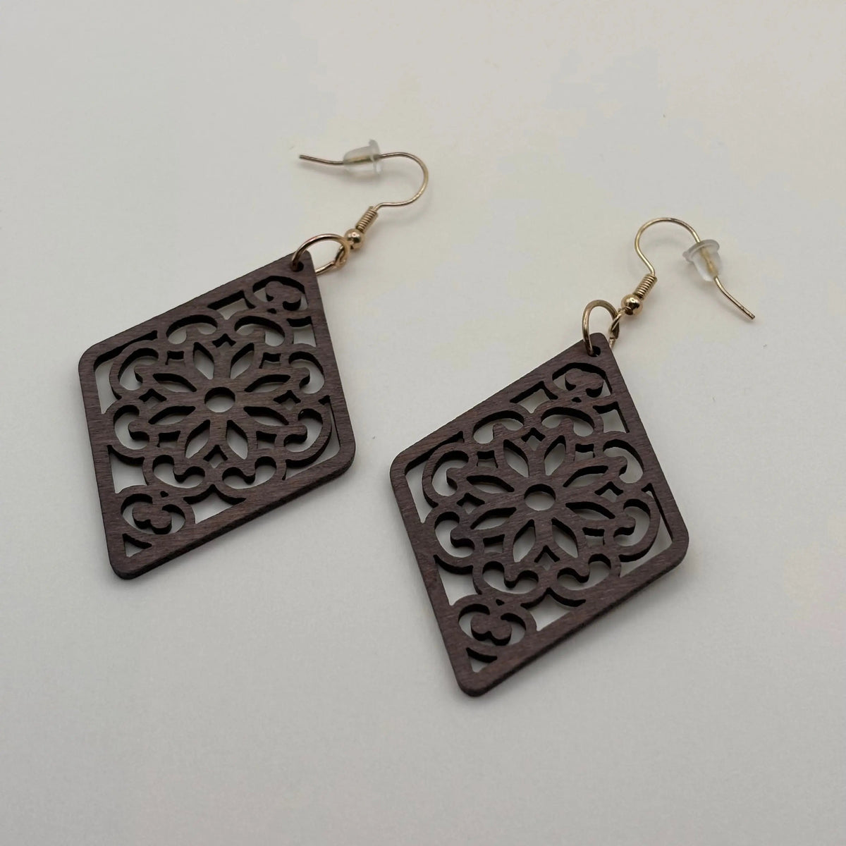 Une paire de boucles d'oreilles avec attache dorée boucle en bois en forme de losange et motif ajouré