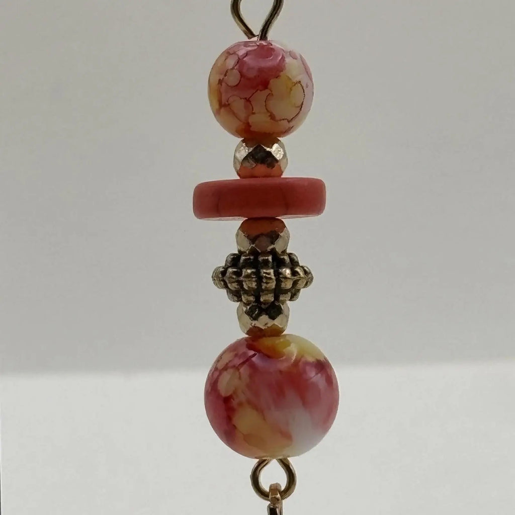 De boucles d'oreilles pendantes avec des perles orangées et jaune et un charms coquillage dorés