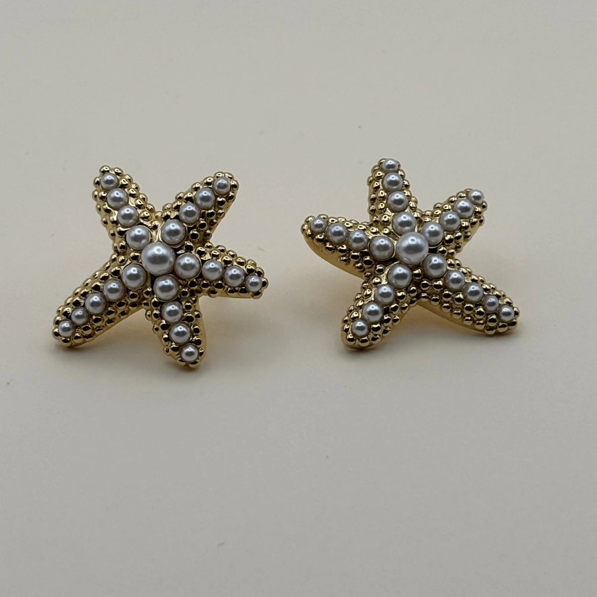 Vue de près de boucles d'oreilles dorées avec motif étoile de mer avec strass en acier inoxydable