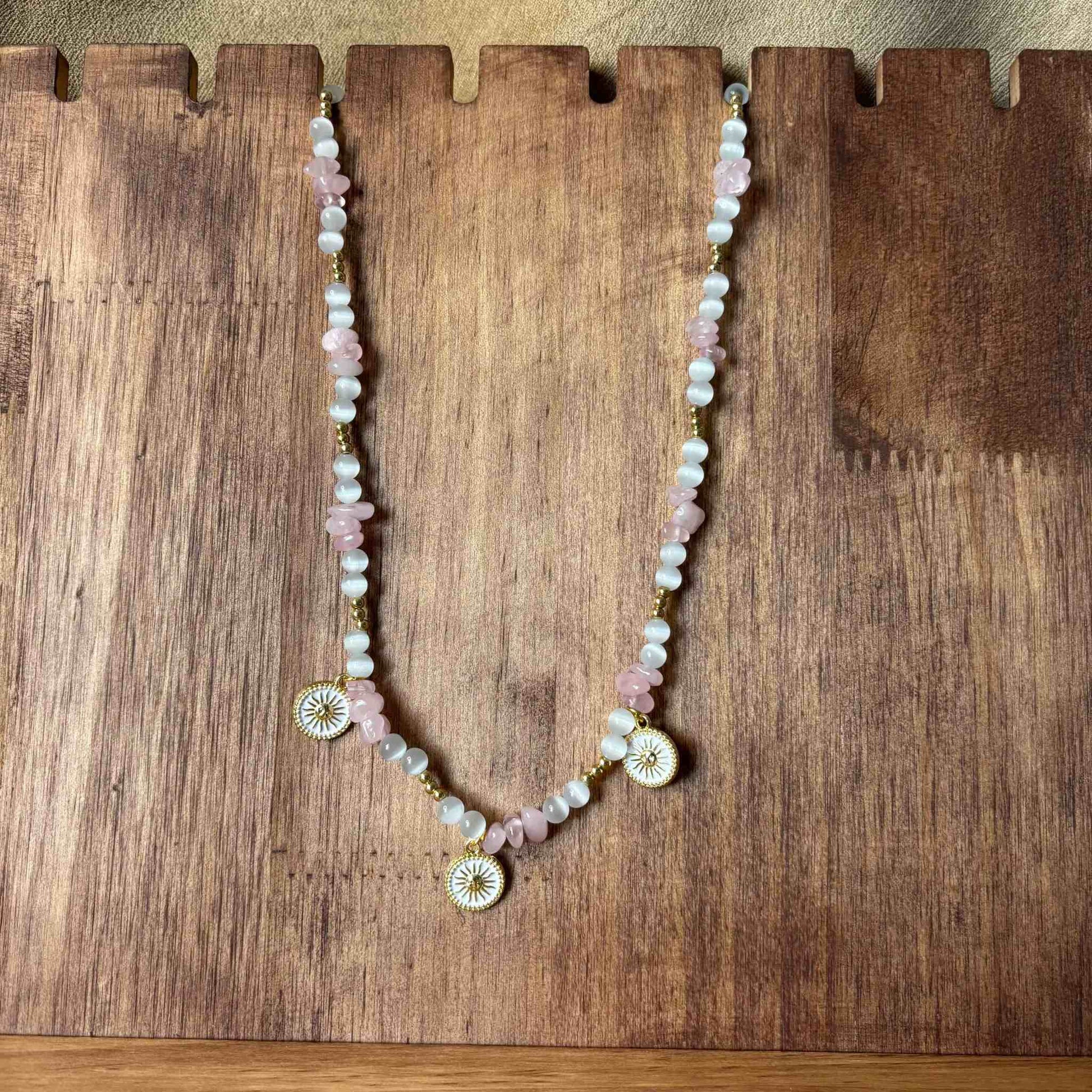 Vue de près d'un collier artisanal en perles rose et blanches avec pendentifs décoratifs en forme de soleil bijou vendu sur le site internet prêtes à briller