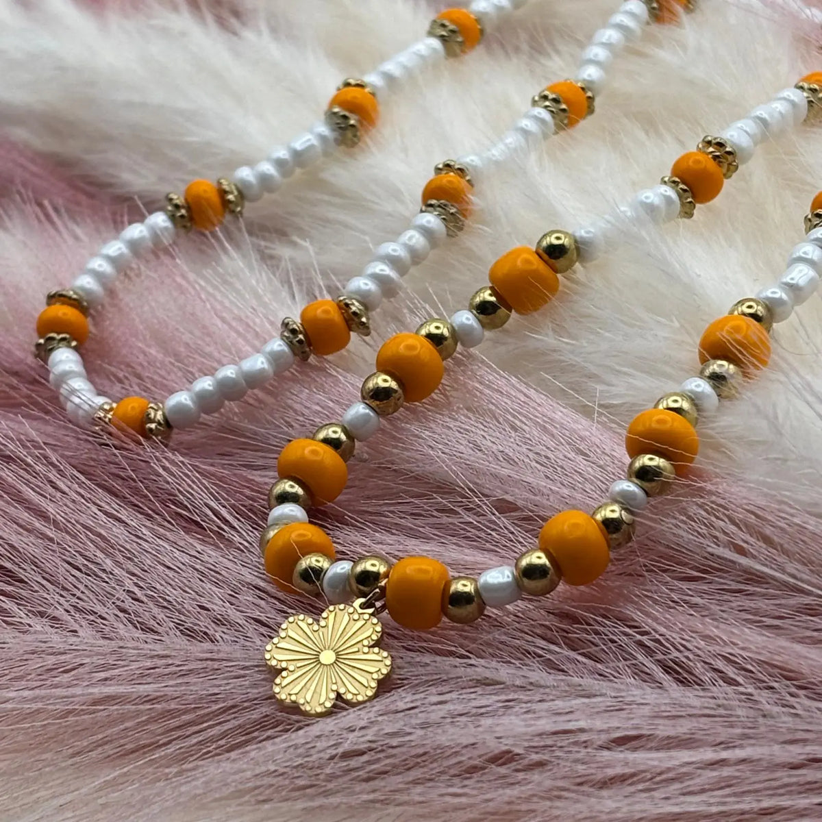 Collier en perles artisanales avec perles oranges et blanches et pendentif soleil doré