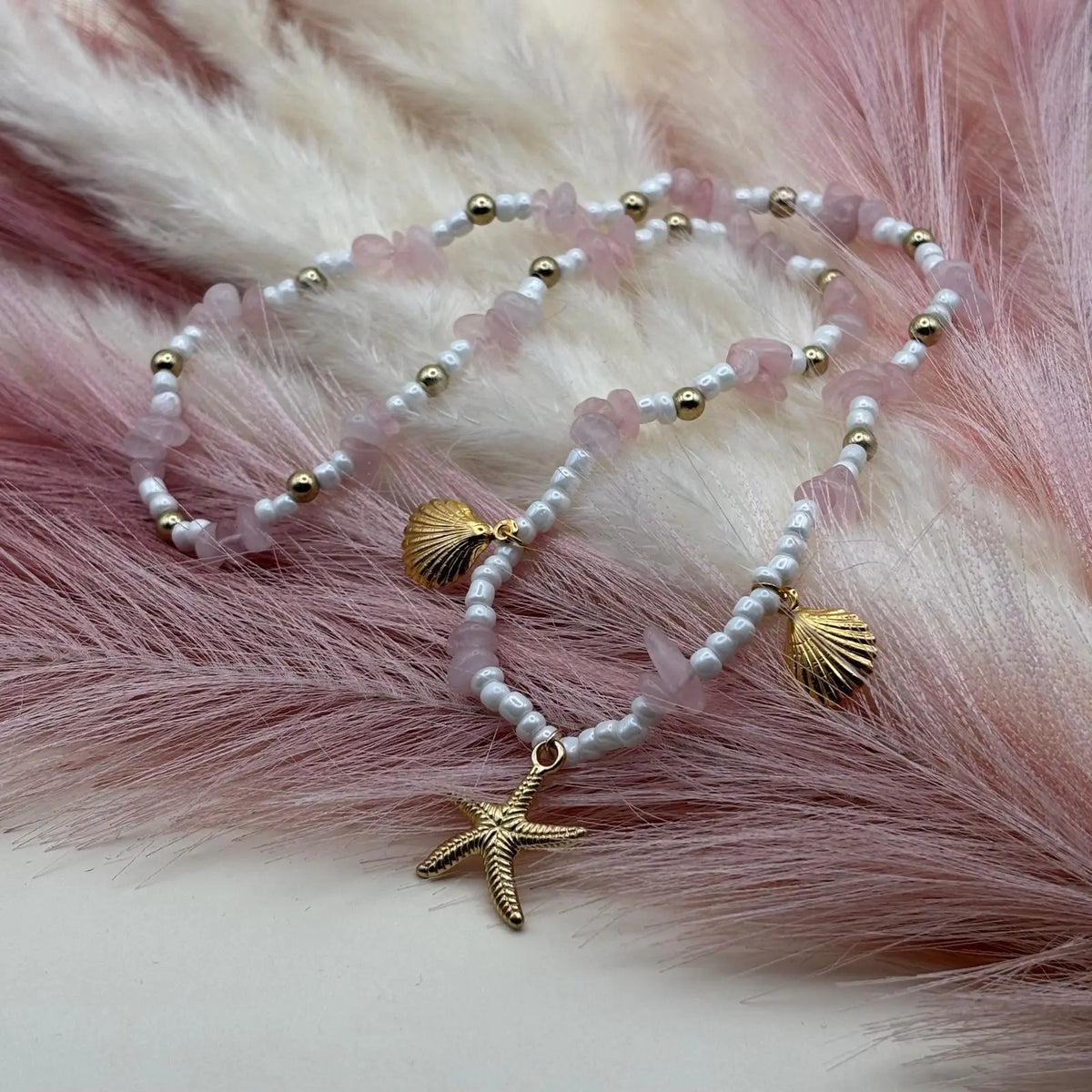 Collier artisanal avec breloques étoile de mer coquillages dorés perles de verre blanche et acrylique rose sur élastique