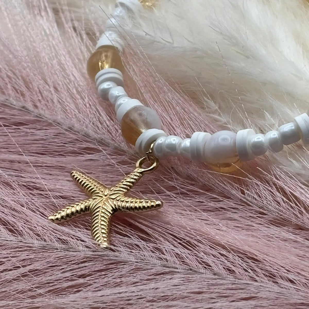Collier artisanal avec breloques étoile de mer coquillages dorés perles de verre blanche et acrylique rose sur un élastique