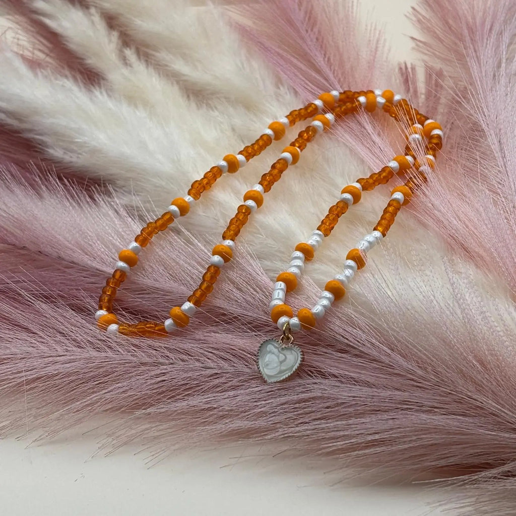 Collier artisanal avec perles orangées et une breloque cœur nacré