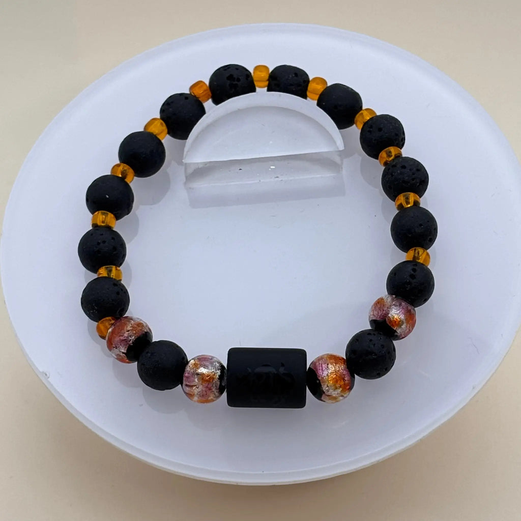 Bracelet en perles noires mates avec perles orange translucides et un cylindre noir gravé en avant