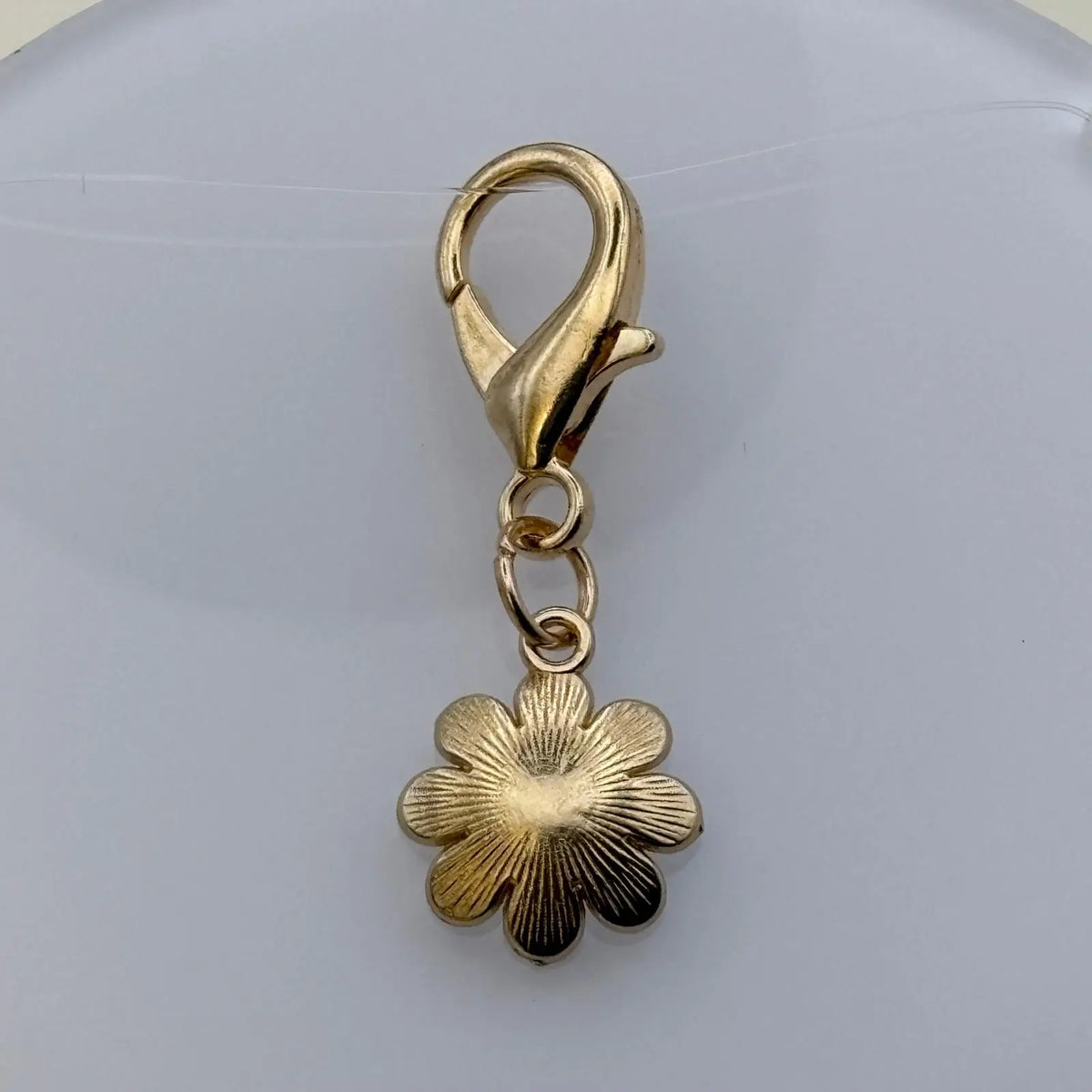 Bijou à accrocher de couleur dorée en forme de marguerite blanche avec fermoir doré