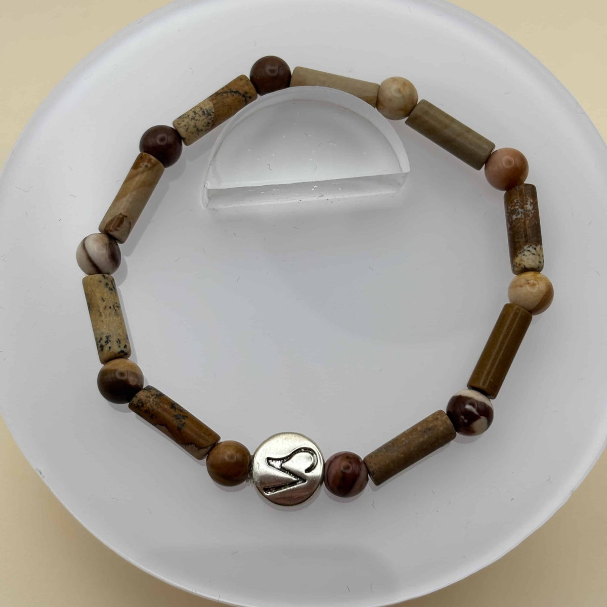 Un bracelet en perles sur élastique avec perles en porcelaine et en verre et médaillon avec le signe du capricorne