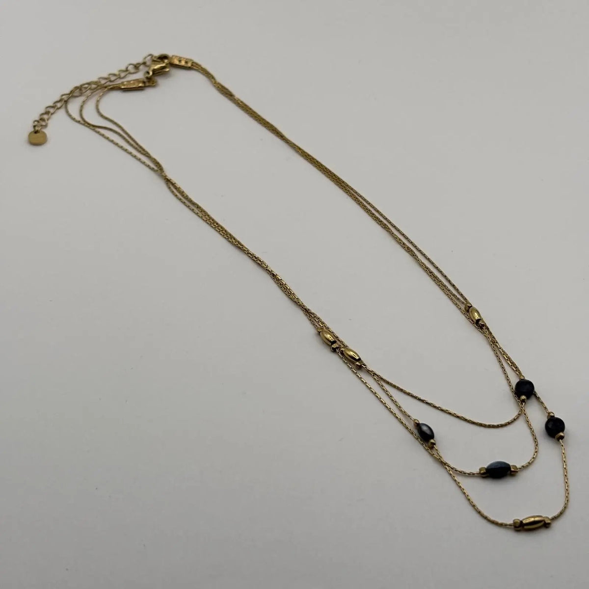 Vue de derrière d'un collier multirangs doré avec perles vertes