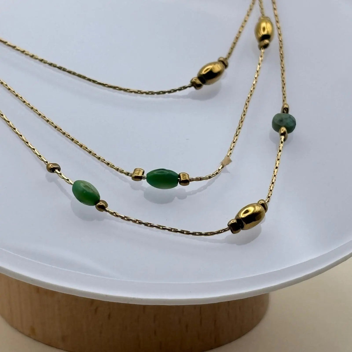 Un collier multirangs doré avec perles vertes