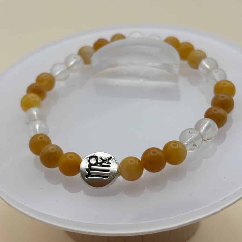 Un bracelet en perles sur élastique avec perles en porcelaine et en verre et médaillon avec le signe  de la vierge Image