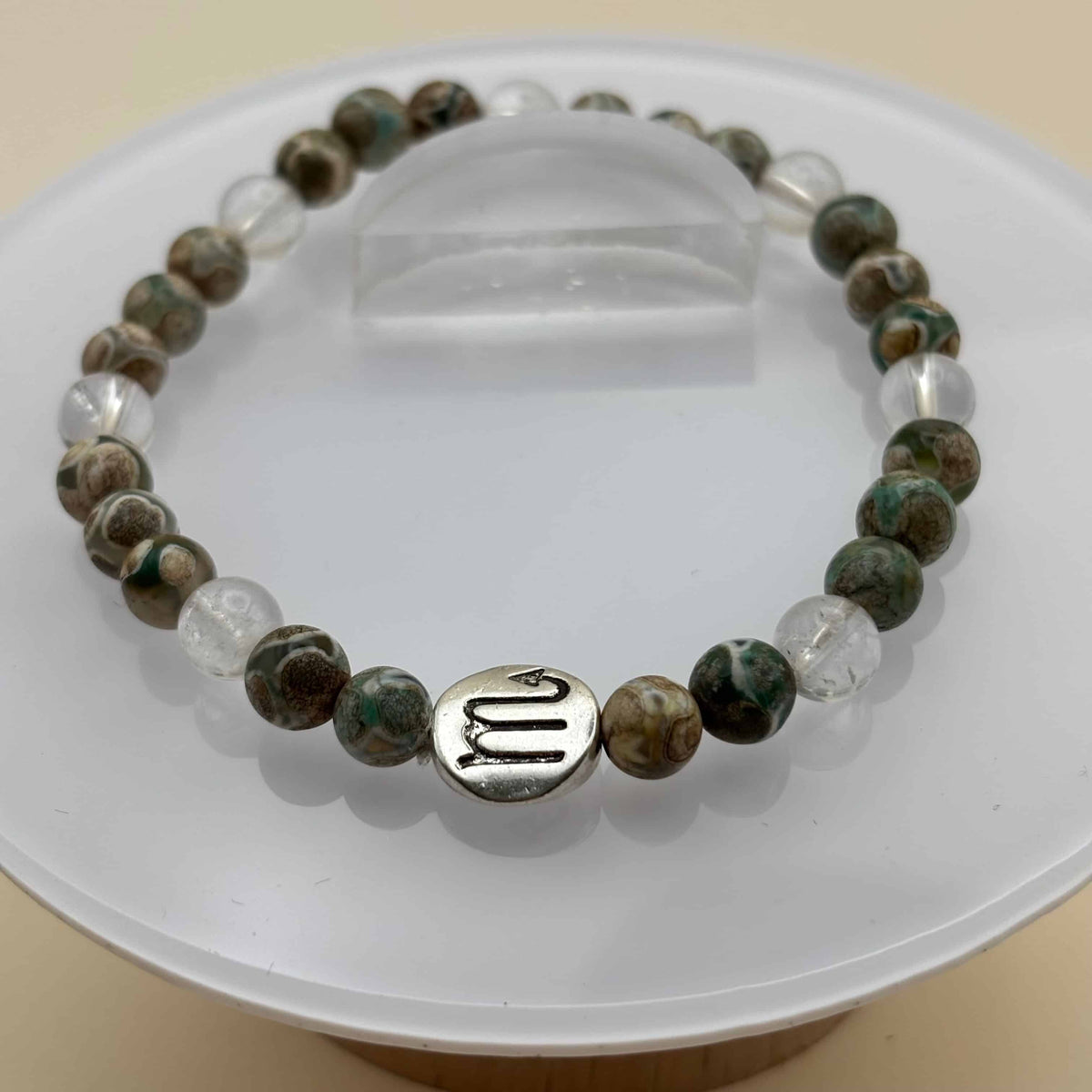 Un bracelet en perles sur élastique avec perles en porcelaine et en verre et médaillon avec le signe du scorpion